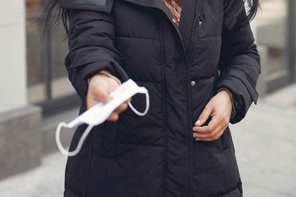 Woman offers a mask to the camera; give-back brands thrive in times of crisis