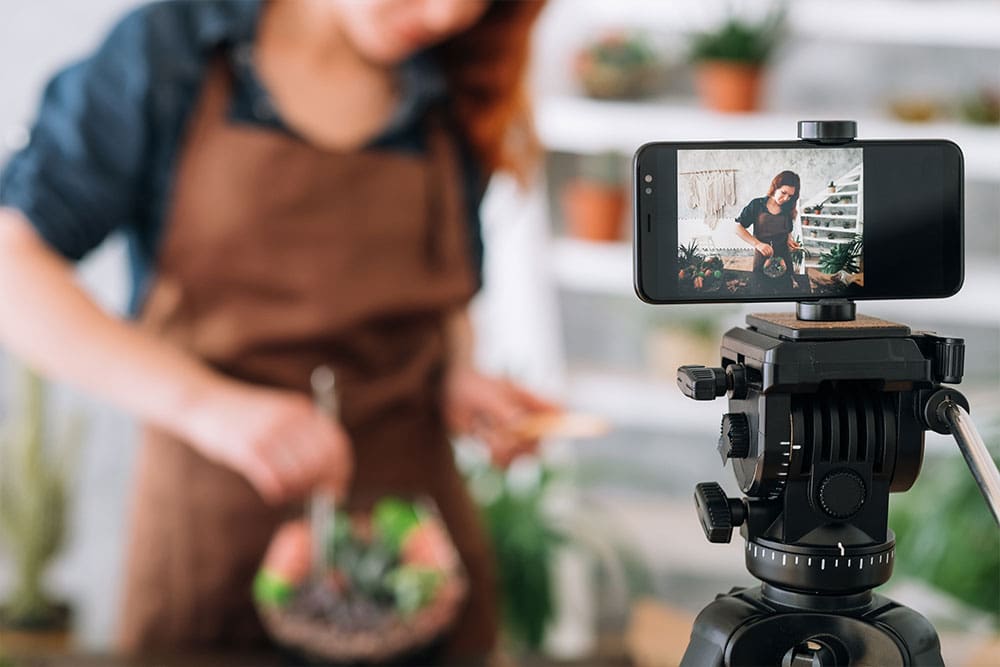 A woman in a leather apron films a video for her content marketing strategy