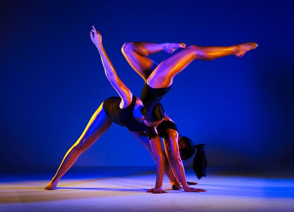 Two dancers posing with purple lighting 