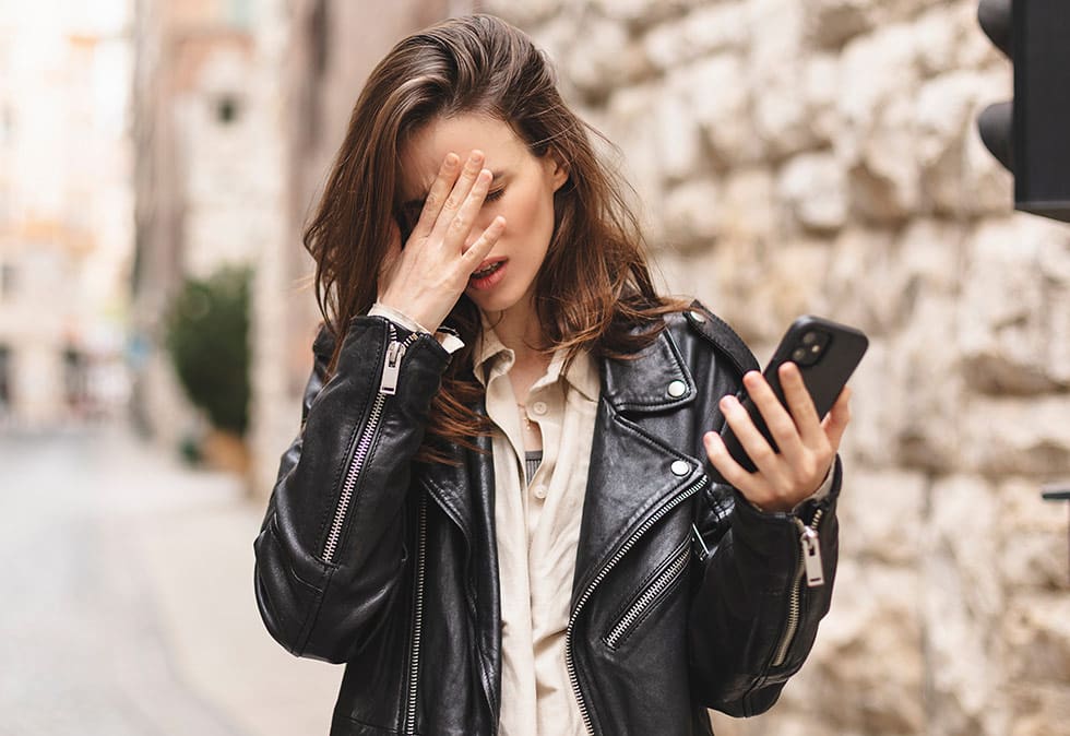 woman holding phone and face palming, seo content writers